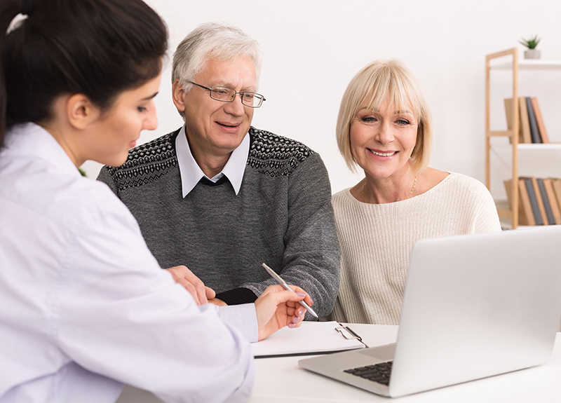 Un personnel soignant montrant à un couple quelque chose sur son ordinateur 