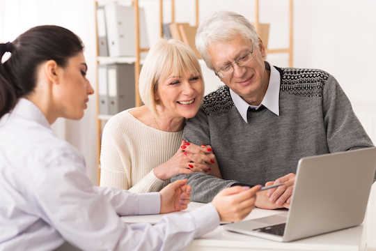 Un docteur montrant quelque chose  à un couple sur l'un ordinateur